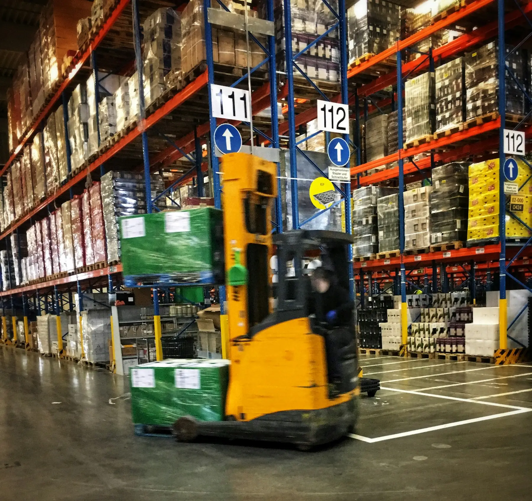 A forklift moving palletised goods through a warehouse aisle